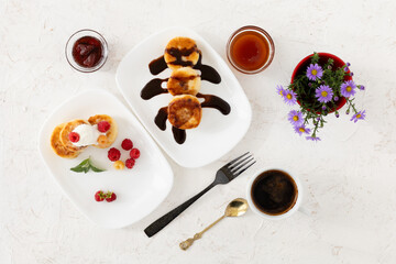 Cup of coffee and curd fritters with sour cream, berries and chocolate on the porcelain plates.