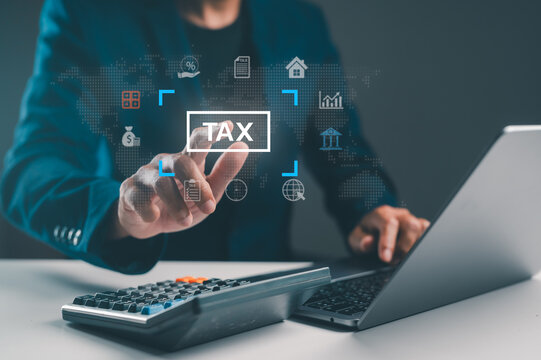 A professional hand interacts with digital tax icons while a calculator and laptop sit on a desk, symbolizing modern financial management and tax preparation.