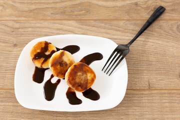 Curd fritters with chocolate on the porcelain plate.