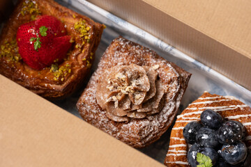 Three beautiful assorted pastries in a cardboard box.