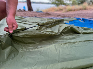 Person setting up camping tent on sandy beach