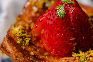 Flaky pastry topped with a glossy strawberry and pistachios.