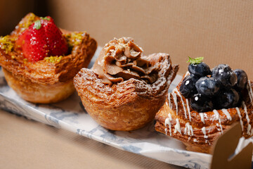 Three beautiful assorted pastries in a cardboard box.