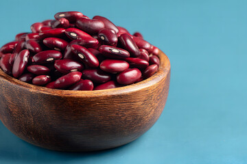Red beans in a wooden bowl on a blue background