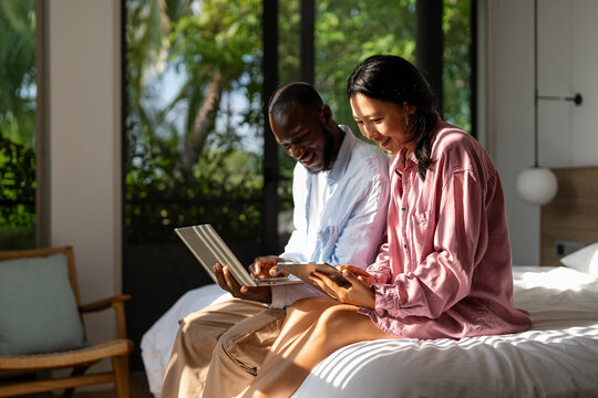 Couple of freelance IT specialists using digital technology devices while working remotely from home