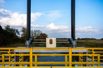 Yellow Rail Water Gate Mechanism Above Flowing Water With Blue Sky For Engineering And Water Management Use