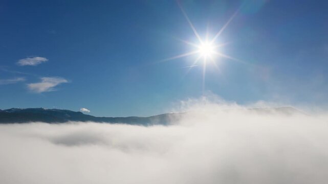 Drone glides above a fog sea toward the rising sun, creating inspirational winter visuals for travel marketing and cinematic landscape projects