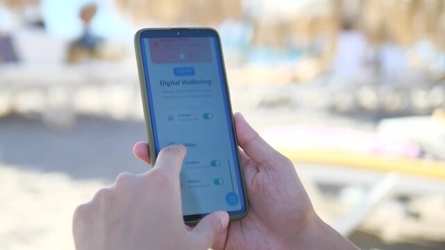 A beachgoer customizes his digital experience by choosing which apps can interrupt his leisure time, using toggle switches to control notifications. Perfect for discussions about healthy technology