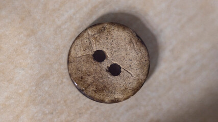 Close-up of a natural wooden button featuring two eyelets