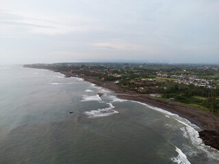 Coastal town and breaking waves along black sand beach