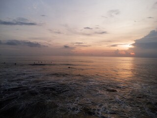 Surfers waiting at sunrise with glowing horizon