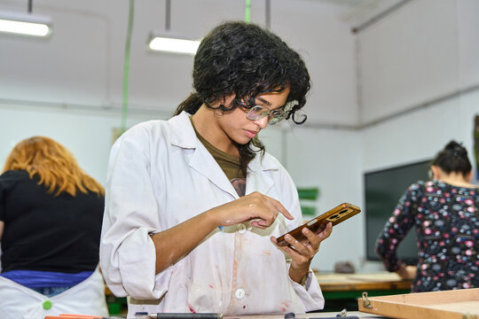 Female student using smartphone in art class workshop