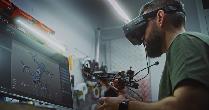 Bearded Man in Tactical Gear Deeply Focused, Using Computer Display and FPV Gear While Working on Drone Electronics. Engineer Utilizing Digital and Physical Tools. Dedication to Military Grade Tech. - Powered by Adobe
