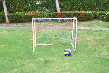  A soccer ball on fresh green grass in front of a soccer goal