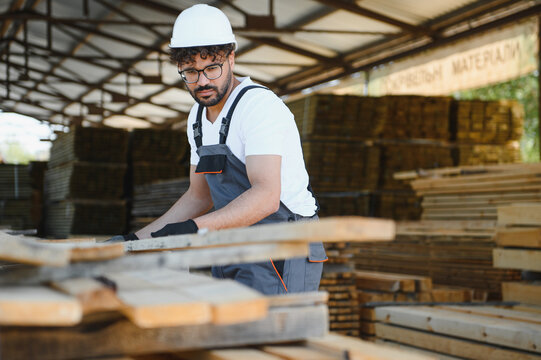 Carpenter working with wood planks in lumber warehouse