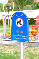 No Dog Pooping sign on a neatly maintained lawn with a crossed-out dog symbol stands next to a sidewalk in a residential area