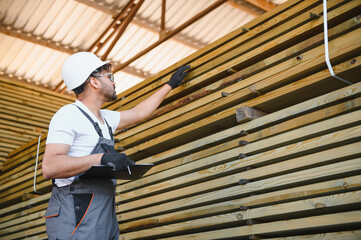 Warehouse worker inspecting lumber using clipboard