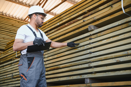 Warehouse worker checking lumber inventory and taking notes