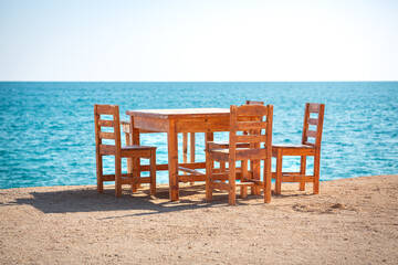 Wooden table and chairs on a beach by the Mediterranean Sea.