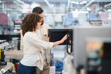 Couple choosing microwave oven in electronics store