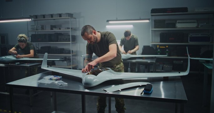 Synchronized Drone Production Team Simultaneously Assembling Large UAV. Technicians in Uniform Simultaneously Assembling UAV Workstations. Concept of Efficiency in Modern Defense Production.