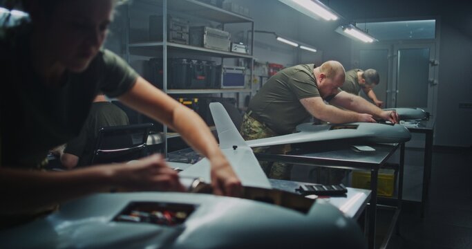 Woman Engineer in Military Uniform Meticulously Installs Internal Components Into Large, Strategic Surveillance UAV. Concept of Professional Expertise and Crucial Role of Women in Defense Technology.