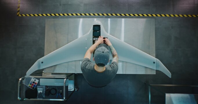 Technician Servicing Large Surveillance Drone. Man Performing Maintenance or Integrating Systems Into Large Aerial Drone. Concept Meticulous Process of UAV Servicing and Quality Control. Top View.