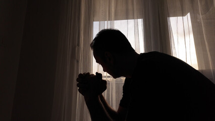 Silhouette of depressed, sad and lonely man in the apartment.