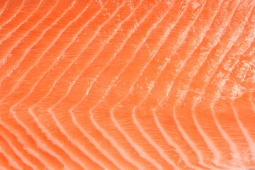 A close-up, full-frame shot of the vibrant orange and pink texture of a raw salmon fillet