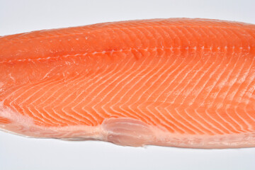 A close-up shot of a raw, skinless salmon fillet, showcasing its vibrant orange flesh, texture, and natural lines on a white background