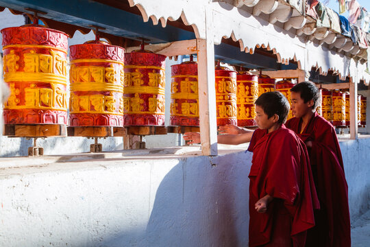 Young buddhist monk spinning prayer wheels, Nepal