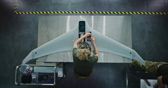 Woman in Camouflage Uniform Working on Next Generation Drone. Female Soldier Installing Electronic Parts Into Surveillance Drone. Concept of Advanced Military Research and Development. Top View.