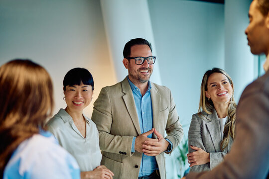 Group of smiling diverse business people collaborating, discussing, and communicating in a casual meeting at a contemporary office workspace - Powered by Adobe