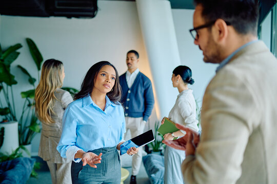 Group of diverse businesspeople collaborating in office setting. Woman proposing idea with tablet. Team working and communicating