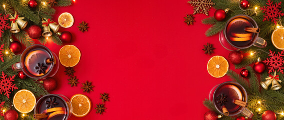 Christmas mulled wine with cinnamon, orange slices, star anise and festive decorations on red background. Warm holiday drink scene with copy space.