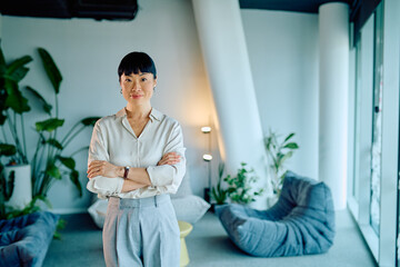 Asian businesswoman standing confidently in a bright, contemporary office space, expressing professionalism, leadership, and success © we.bond.creations