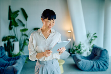Asian businesswoman using digital tablet in modern office, embracing technology for corporate communication and business