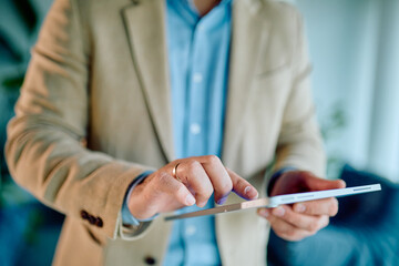 Businessman's hands holding and touching a touchscreen tablet, engaging with technology for business and lifestyle tasks
