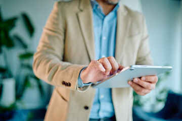 Professional man wearing a blazer and blue shirt, actively using a digital tablet for work, connecting with technology and digital solutions