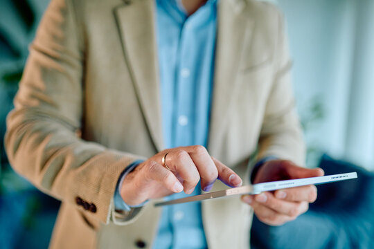 Businessman's hands holding and touching a touchscreen tablet, engaging with technology for business and lifestyle tasks