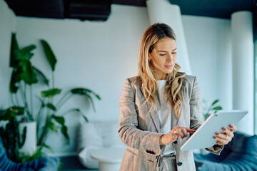 Professional woman using digital tablet, tapping on screen, working in a modern comfortable office building, a symbol of business and tech