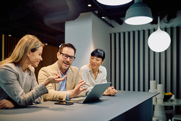 Diverse business team smiling and engaging in an informal discussion, sharing ideas while working together on a laptop