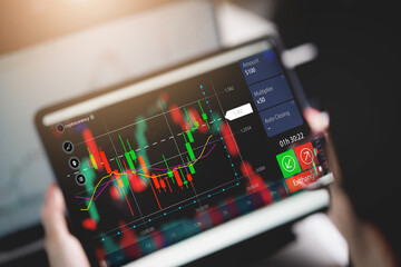 A person is holding a tablet with a stock market graph on it