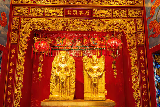 Golden deity statues with red and gold decorations inside Suphanburi shrine