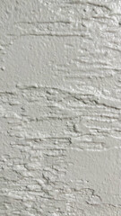 Close-up of a light-colored wall with a rough, uneven texture and horizontal grooves