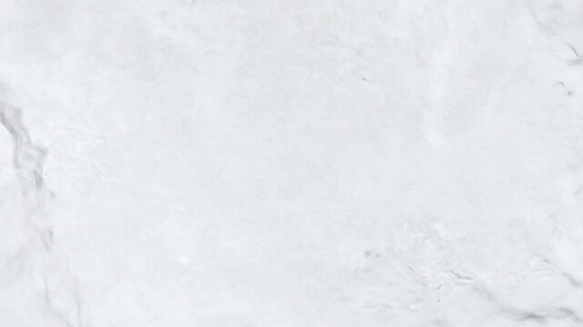 Close-up of a white marble surface with light gray veining creating a cloudy and textured look