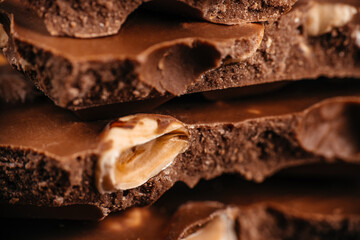 Macro texture of broken milk chocolate with whole hazelnuts, layered in a warm close-up composition, ideal for premium confectionery advertising, dessert branding, packaging design