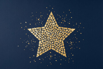 A golden star made of a mosaic of small sparkling pieces on a dark blue background. Festive, luxury concept for celebration, award, or holiday.