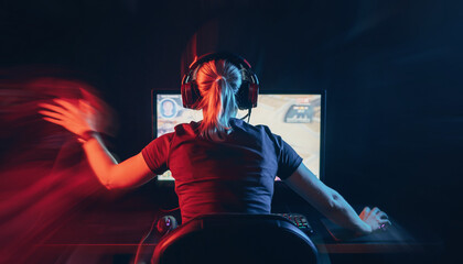 A person with headphones intensely gaming on a computer in a dark room with vibrant red and blue neon lighting and motion blur.