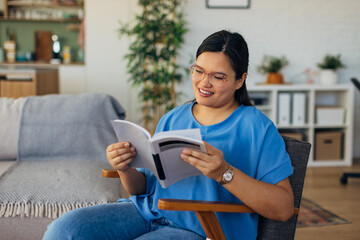 In a well-lit living room, a smiling woman reads a book, creating a serene and cozy atmosphere that encourages relaxation and positive emotions alongside modern furniture details.